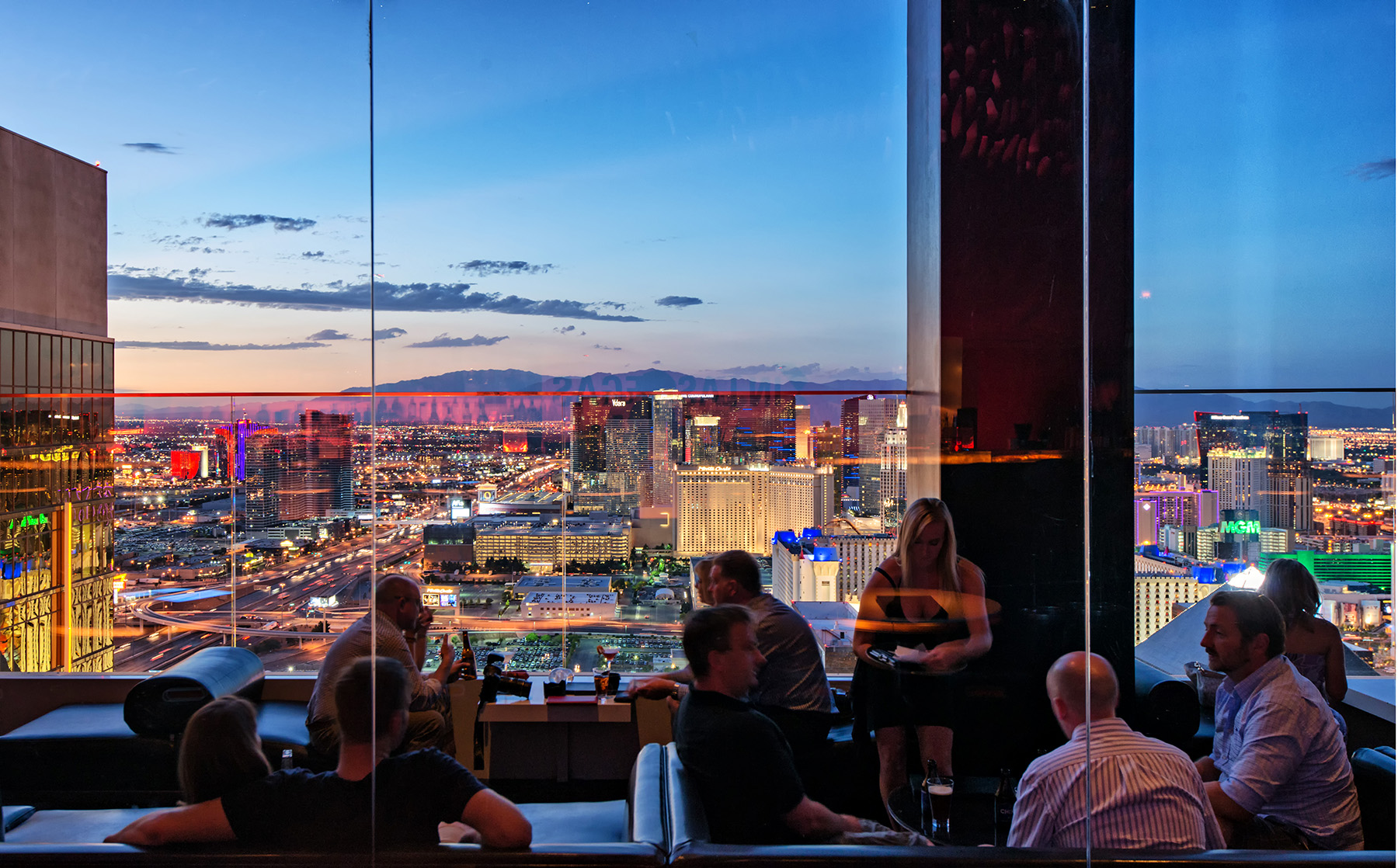 People enjoying drinks and cocktails at the THEHotel MiX Lounge terrace and Las Vegas Skyline at the blue Hour